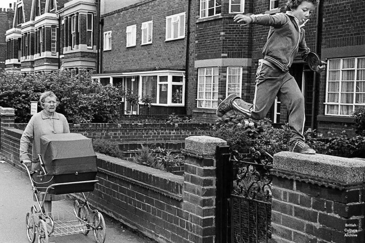 A photograph by Luis Bustamante shows a boy running along a wall in Hull in the 1970s.